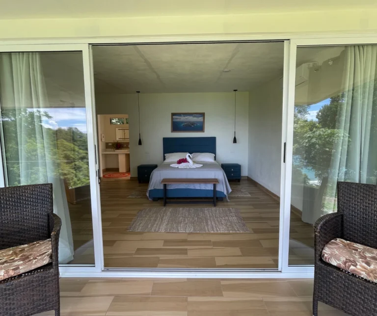 Spacious deluxe room at Casa Sollevante with ocean-view sliding doors, king bed and modern minimalist design.