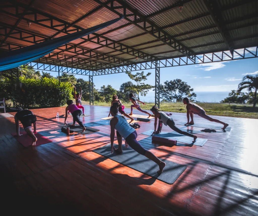 Devaya Yoga group practicing on the ocean-view yoga deck in Montezuma, Costa Rica during a transformational retreat.